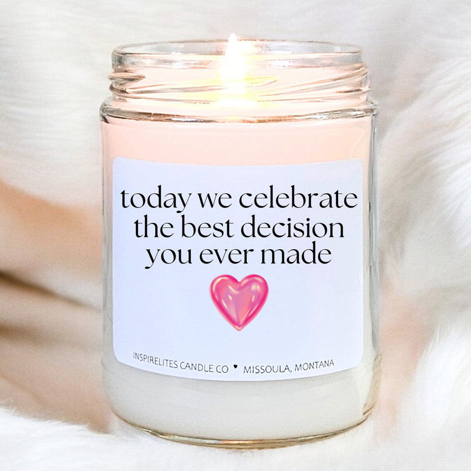 Candle with a label reading 'today we celebrate the best decision you ever made' on a soft white background